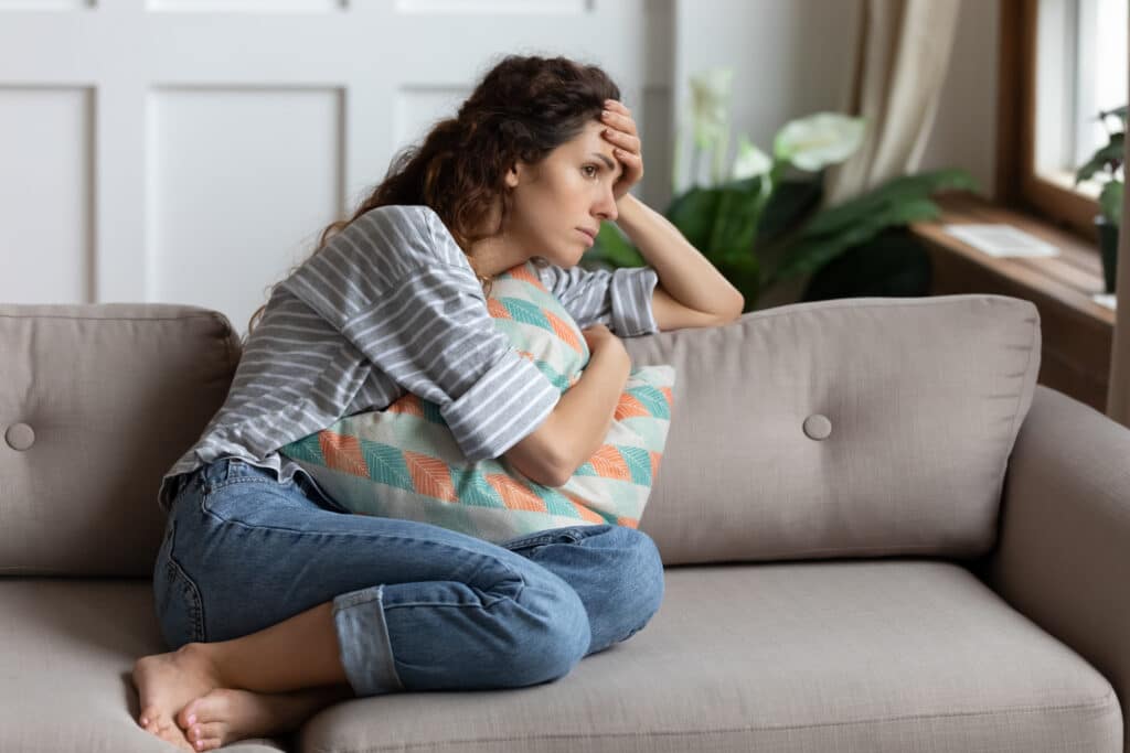 Frustrated Young Lady Sitting On Sofa