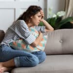 Frustrated Young Lady Sitting On Sofa